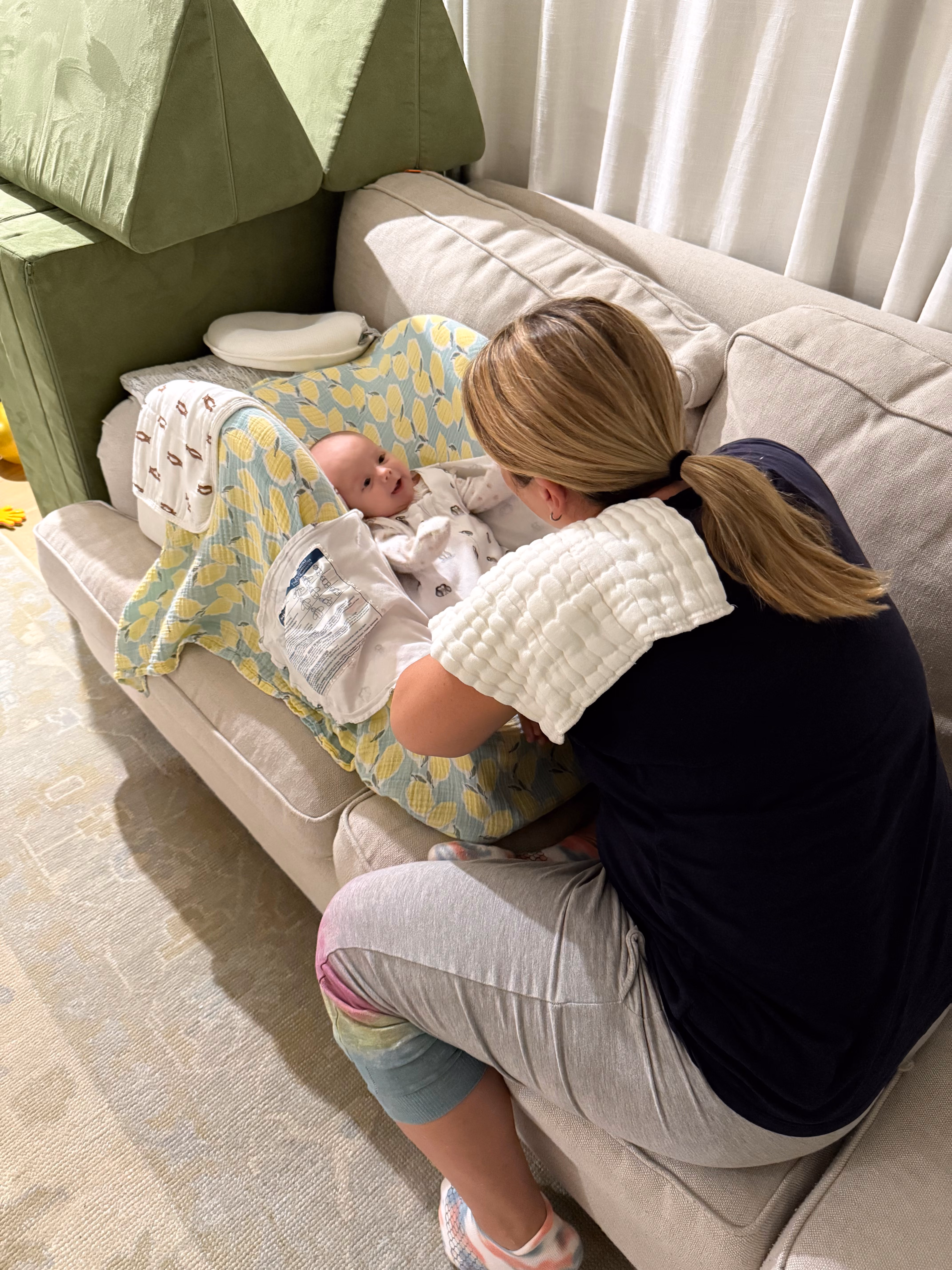 A mother holding her swaddled newborn against a plain, calm backdrop.